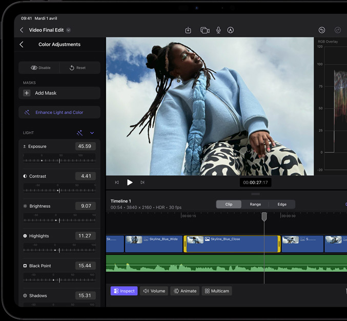 iPad Pro, face avant, cadre d’écran noir, écran affichant une app de montage vidéo avec la photo d’une mannequin vêtue d’un manteau bleu et d’un pantalon imprimé noir et blanc, panneau d’ajustement des couleurs ouvert sur la gauche avec divers effets vidéo et curseurs, timeline en bas avec plusieurs plans vidéo et pistes audio