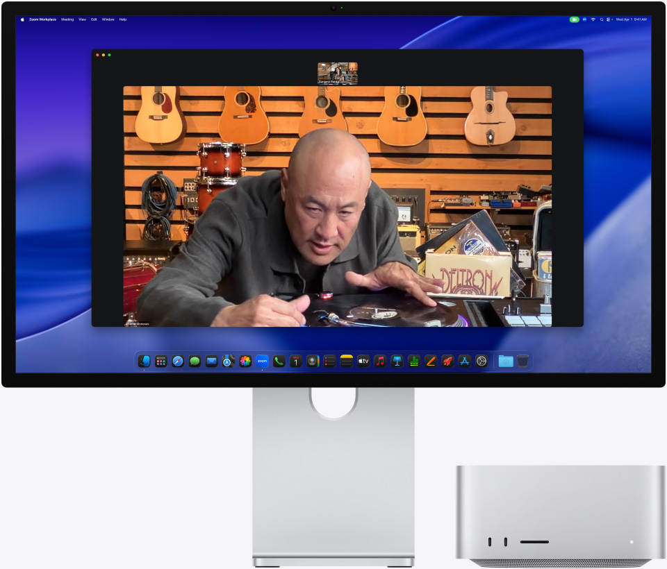 Під час відеовиклику на Studio Display XDR із Mac Studio, розміщеним під ним, людина в музичному магазині уважно розглядає програвач платівок