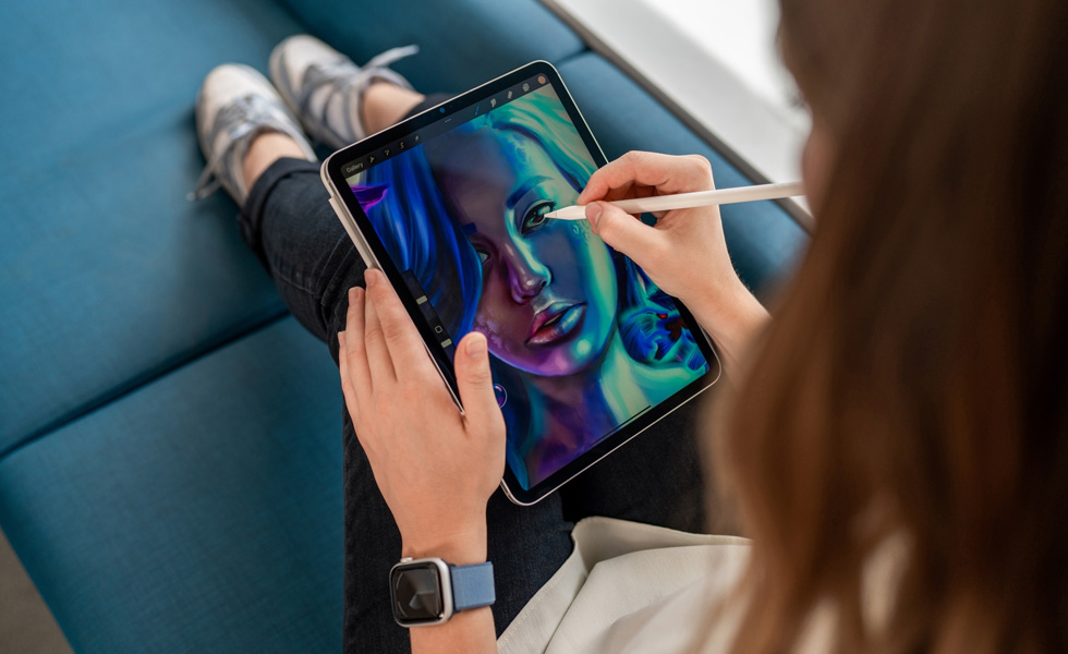 นักศึกษาคนหนึ่งถือ iPad ไว้บนตักระหว่างที่ใช้ Apple Pencil วาดภาพในแอป Procreate