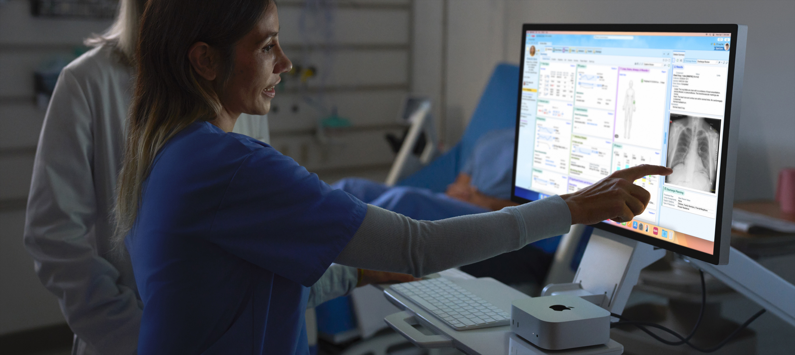 صورة لممرضة تشير إلى صورة الأشعة السينية للمريض على iMac.‏